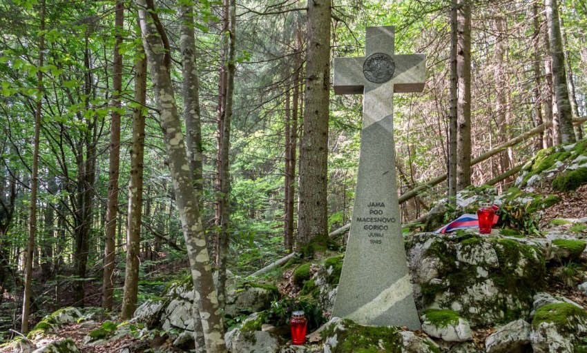 Jama pod macesnovo gorico and cross in front.